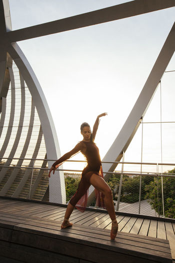 Ballerina dancing on bridge against clear sky