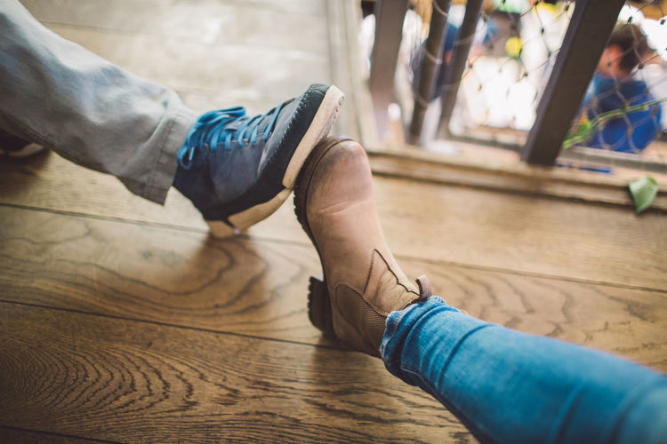 Low section of people wearing shoes on wooden floor