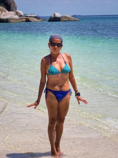 Midsection of woman in bikini at beach