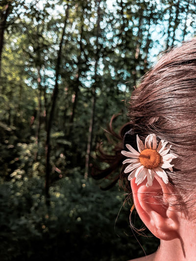 Close-up of woman wearing flower in forest