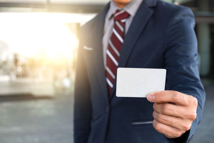 Midsection of businessman holding card