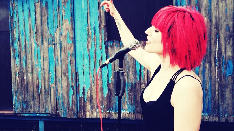Young woman with dyed hair singing into microphone