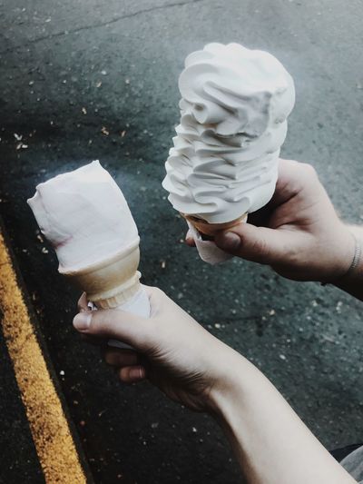 Cropped image of hands holding ice creams on street