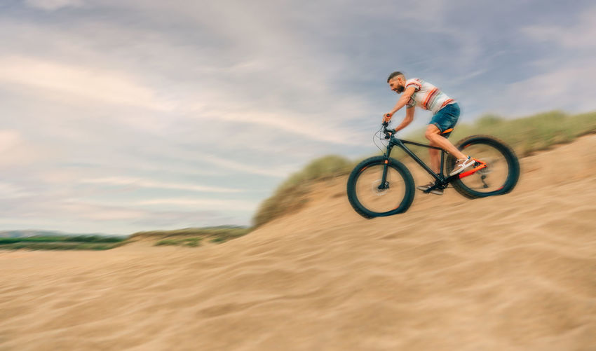 Man riding fast fat bike through beach dunes