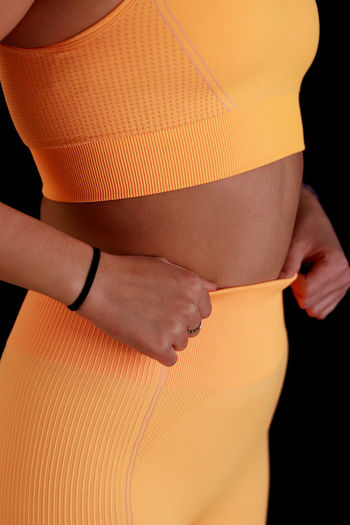 Midsection of woman with arms crossed in workout clothing 