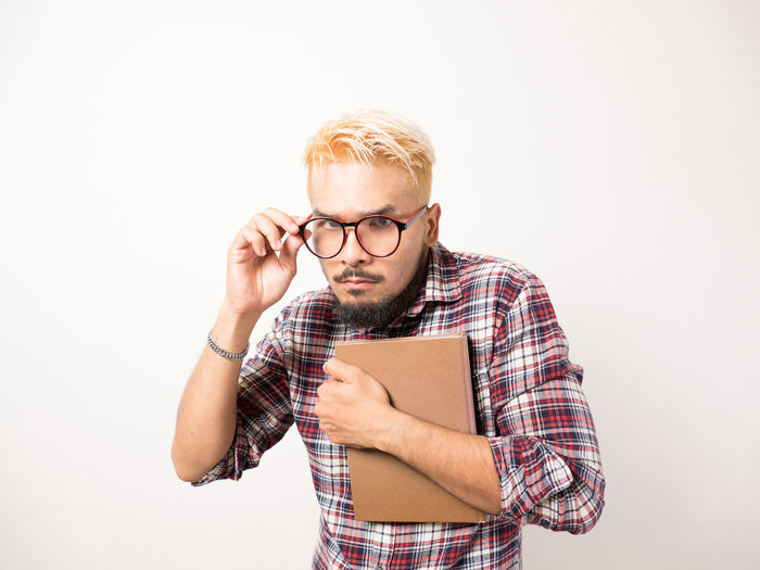 Young man wearing hat standing against white background