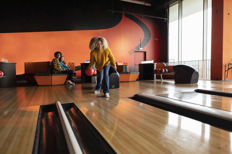 Young woman playing throwing ball at bowling alley