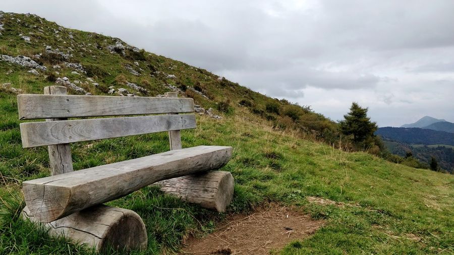 Wooden bench on landscape against sky