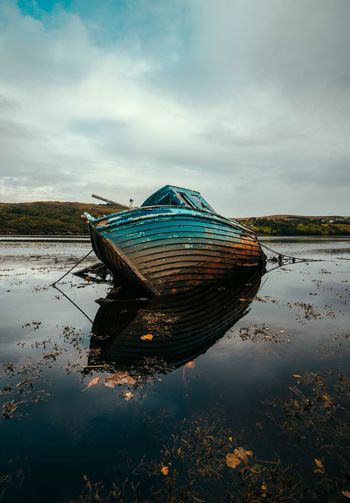 Boat moored in lake against sky