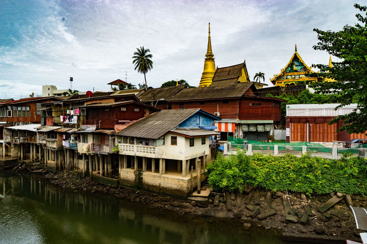 Temple amidst houses by river against sky in town at chanthaburi