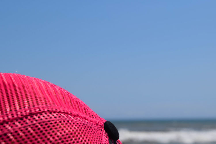 Cropped pink baseball cap against clear blue sky