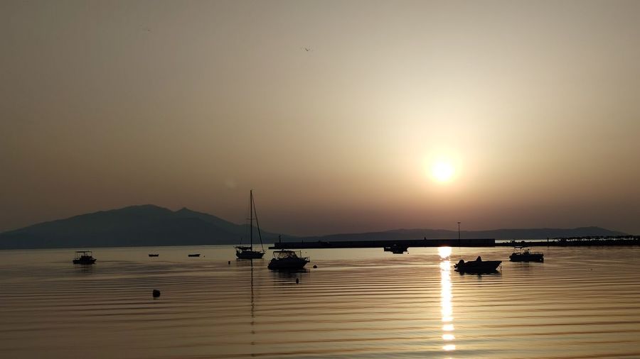 Silhouette sailboats in sea against sky during sunset