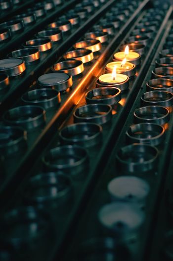 Three burning candles in between many candles at church