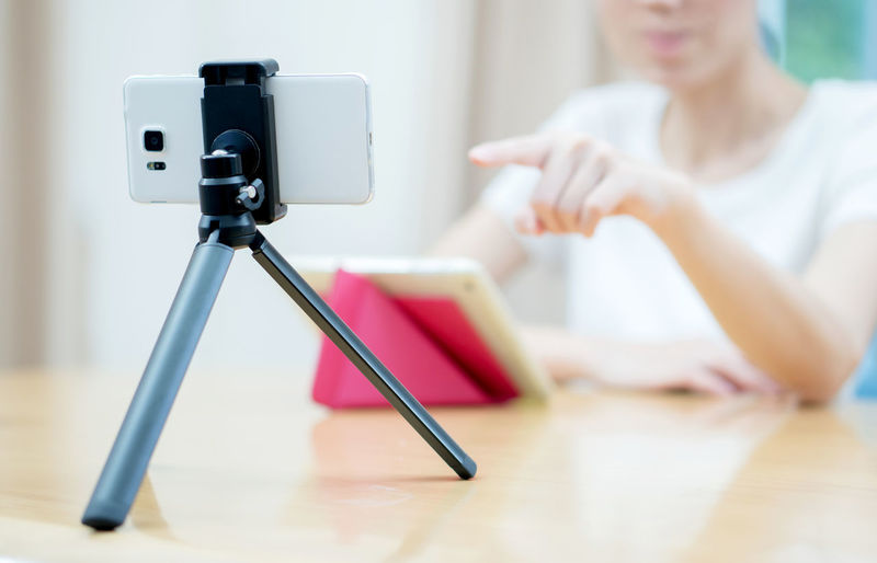Midsection of woman photographing with smart phone on table