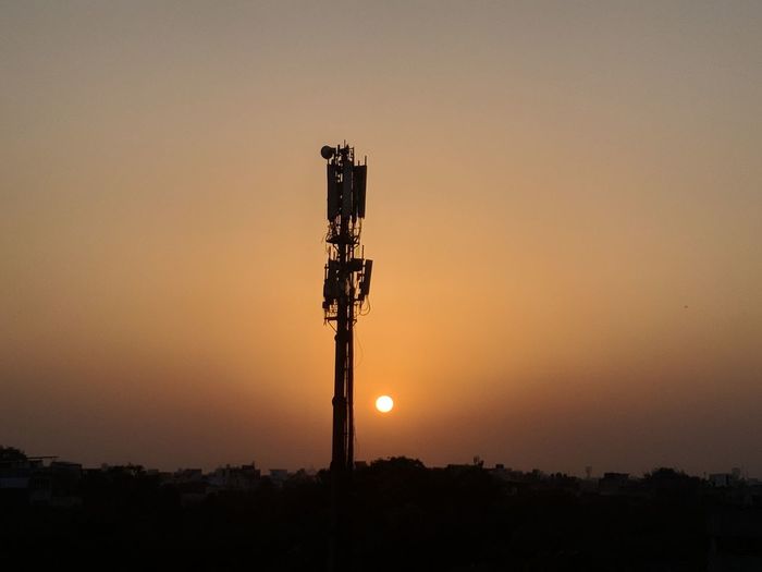 Silhouette communications tower against sky during sunset