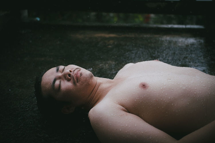 Portrait of young man lying on wet floor
