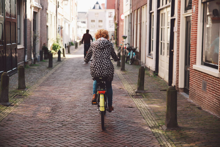 Rear view of woman riding bicycle on road