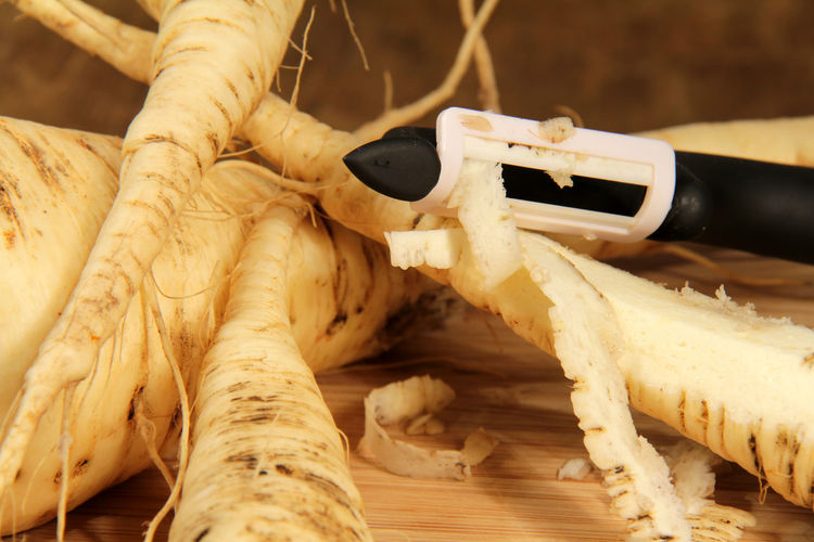 Close-up of peeler peeling vegetable on table