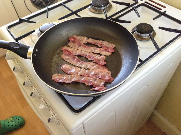 High angle view of bacon in cooking pan on stove at home
