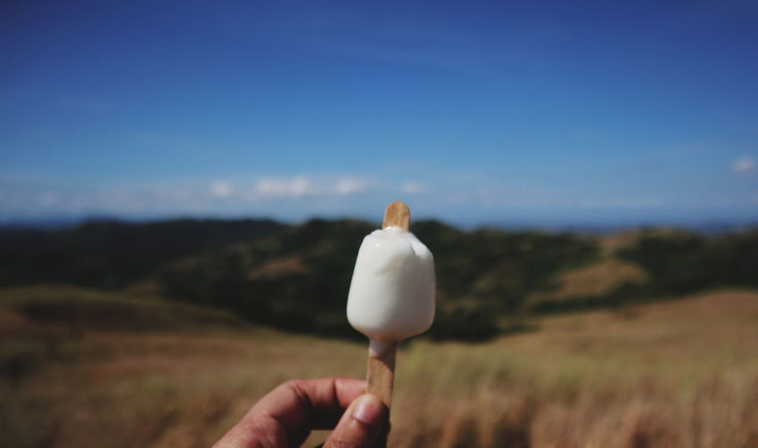 Person holding ice cream against sky