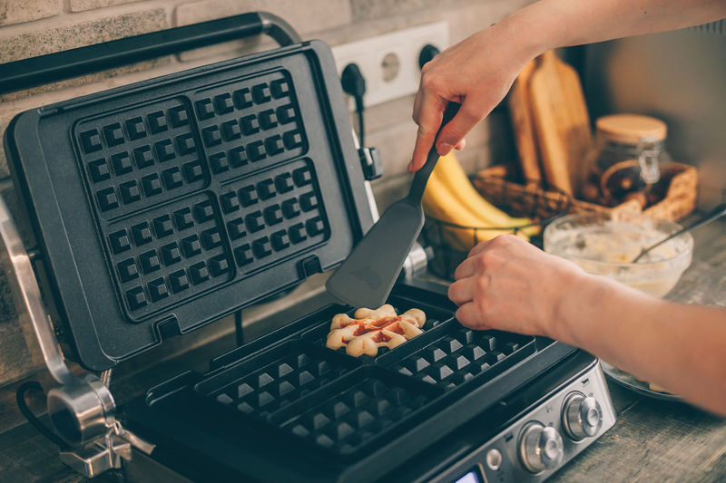 Cropped hands of woman preparing waffles in kitchen