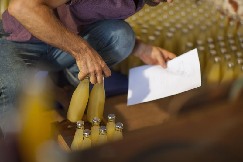 Man putting bottles of juice in wooden boxes in warehouse