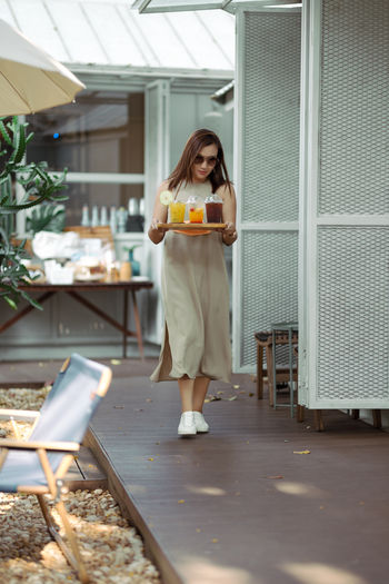 Full length of young woman using digital tablet while standing in cafe