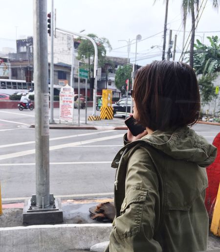 Woman talking on phone at sidewalk in city