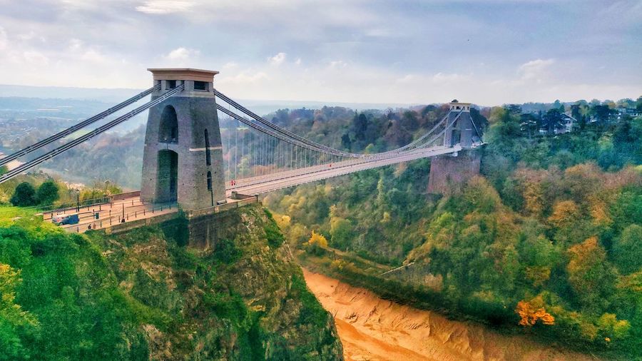 Bridge over mountain against cloudy sky