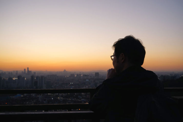 Man in city against clear sky during sunset