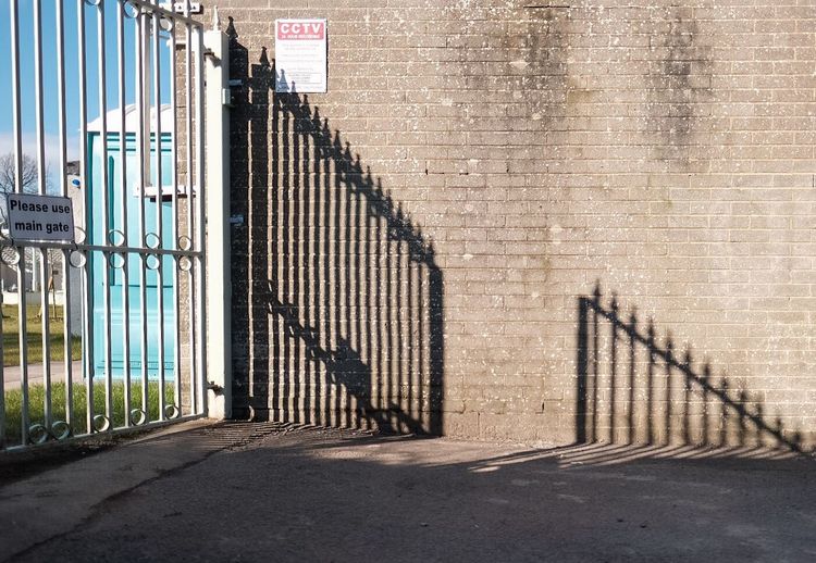 Shadow of metal gate on brick wall at dollar park