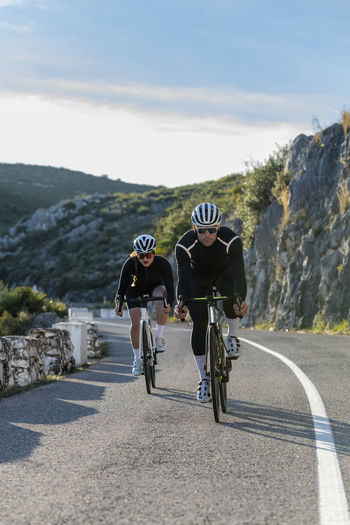 Sportsman and sportswoman cycling on costa blanca mountain pass in alicante, spain