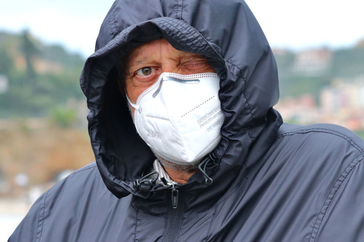 Portrait of senior man wearing mask standing outdoors