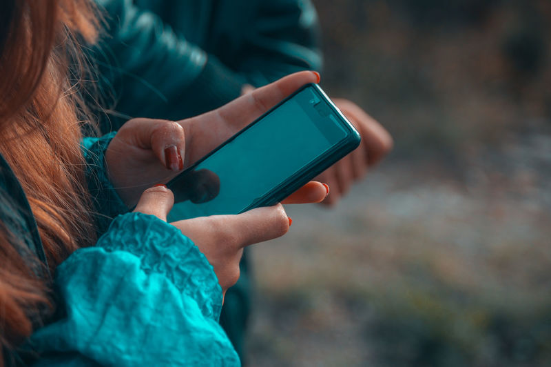 Cropped image of woman using mobile phone outdoors
