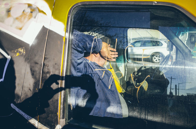 Reflection of man using mobile phone in car