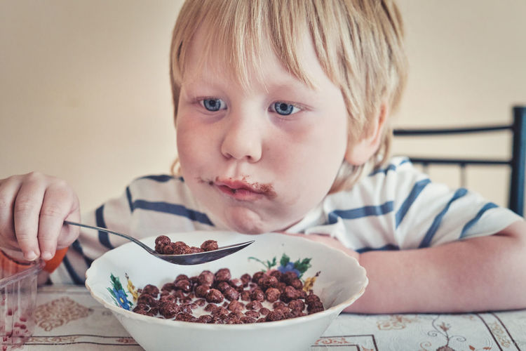 Close-up of cute boy eating food at home
