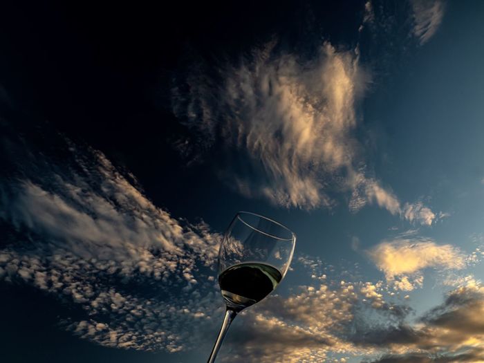 Low angle view of wine glass against sky during sunset