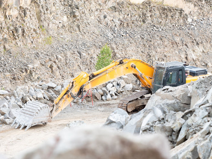Excavator during earthmoving work at open-pit mining on gravel quarry background. loader machine 
