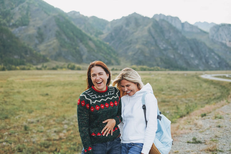 Happy young women travellers on road against beautiful mountain landscape
