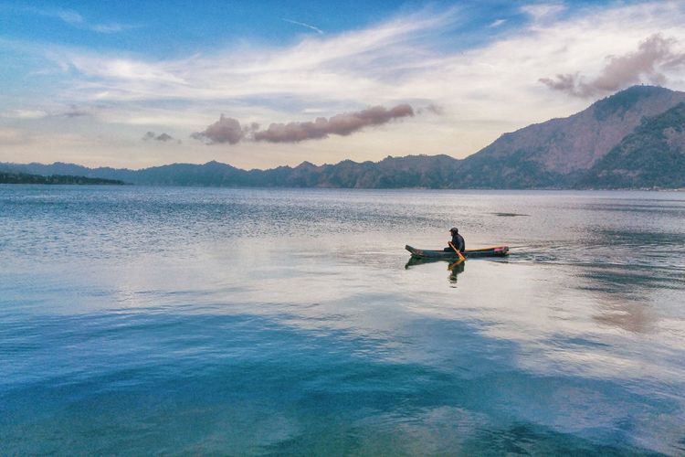 Man kayaking in lake against sky
