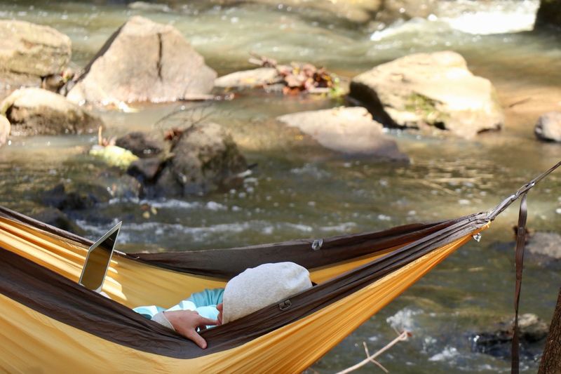 Man lying in hammock near river