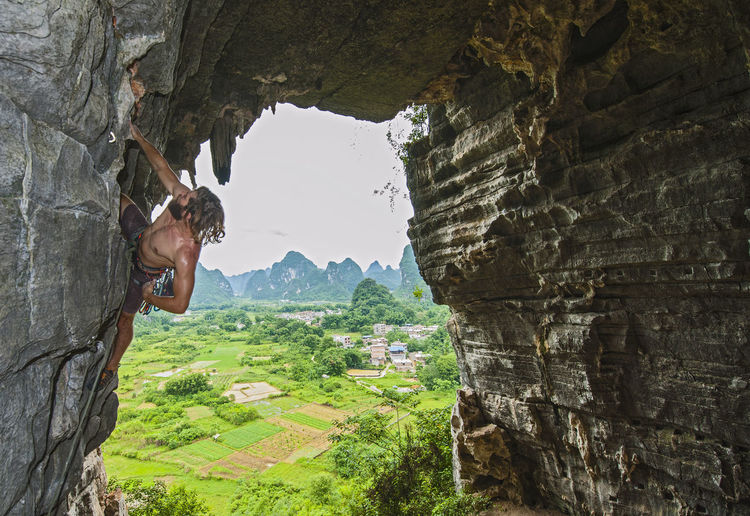 Young male climber climbing at treasure cave in yangshuo, china