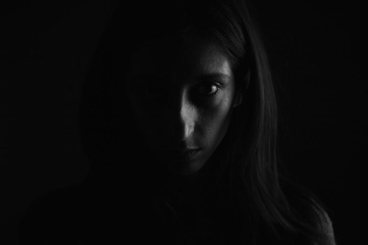 Close-up portrait of serious woman against black background