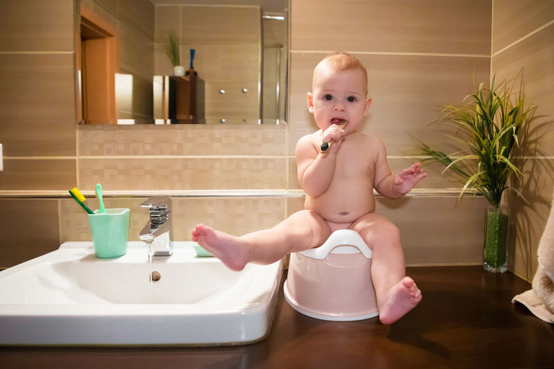 Full length of cute baby girl sitting by sink