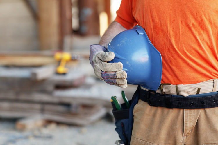Close up of a male construction worker holding a hard hat