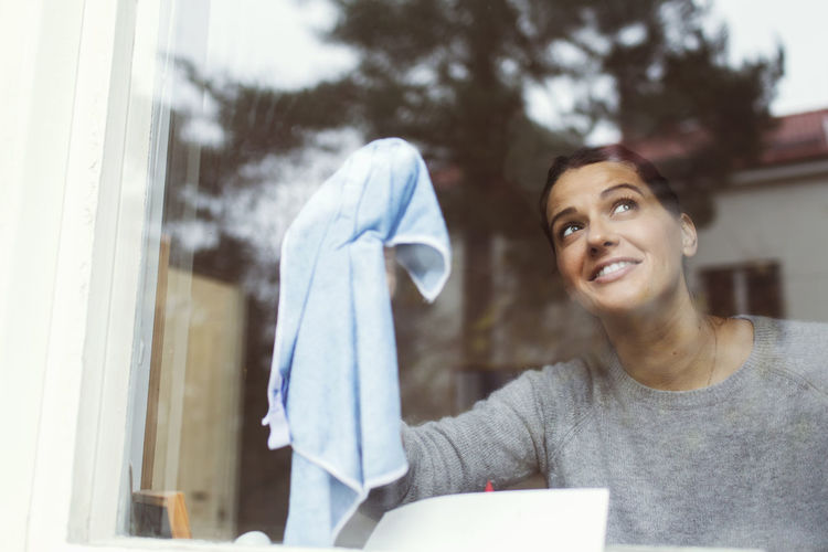 Woman cleaning glass of house window