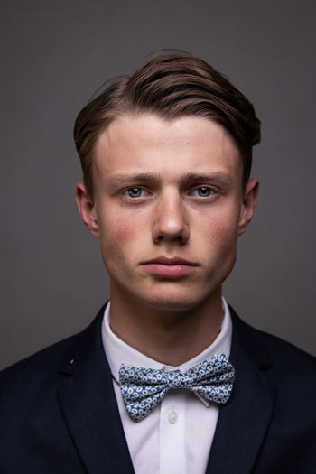 Portrait of young man in a suit against gray background. 