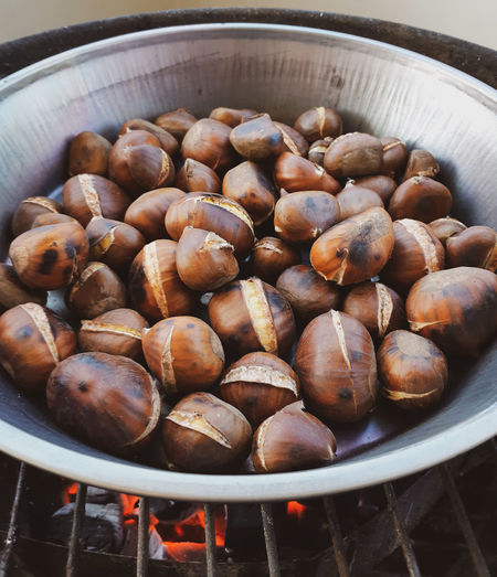 Sweet chestnuts roasting on frying pan close-up.