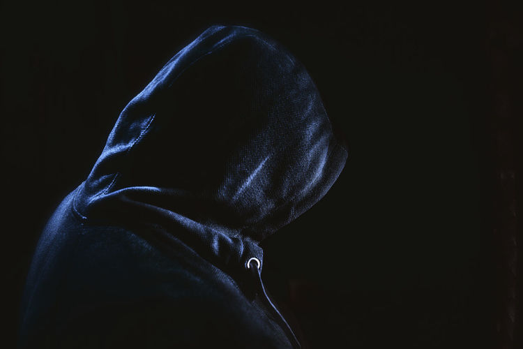 Close-up of person covering face against black background