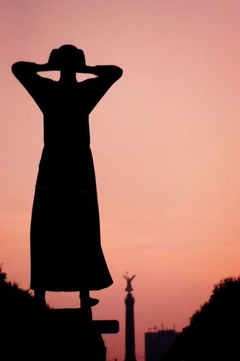 Silhouette of woman statue standing against sky during sunset shouting 